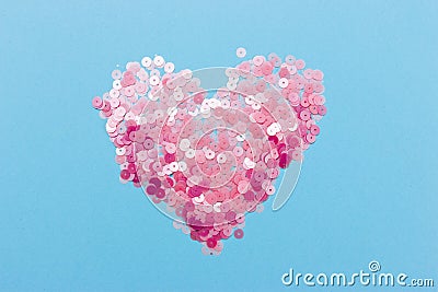 Decorative heart shape made of pink sequins on an isolated blue background. Stock Photo