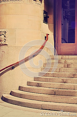 Decorative historic stone building. Facade with ornament design. Granite stairway entrance construction. Wooden double door with Stock Photo