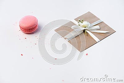 Decorative kraft envelope with bow and pink macaron isolated on white, wedding invitation card concept Stock Photo