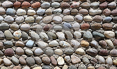 Decorative pebbles wall, made of many small rocks with different colors on a cement background Stock Photo