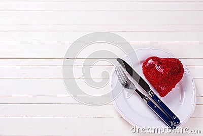 Decorative red heart, knife and fork on white plate on white w Stock Photo