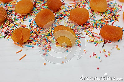 Decorative sprinkles border and dried apricots on white background. Multicolor Sugar confectionery powder and dried apricots in th Stock Photo