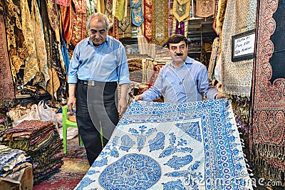 Decorative textiles in city bazaar, Iranian seller demonstrates Editorial Stock Photo