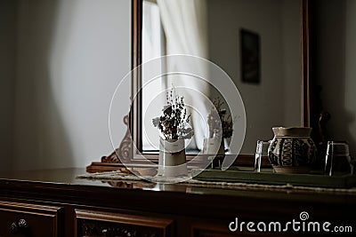 Decorative vase with a bouquet of fresh multicolored flowers on a dresser in front of a mirror Stock Photo