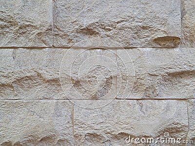 Decorative wall, built of hewn stone slabs of beige color Stock Photo