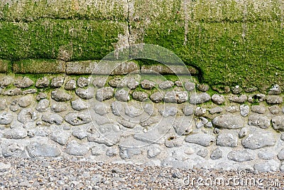 Decorative weathered old wall by the sea in Normandy, stone in part concrete, section, with algae and moss, copy space, space for Stock Photo