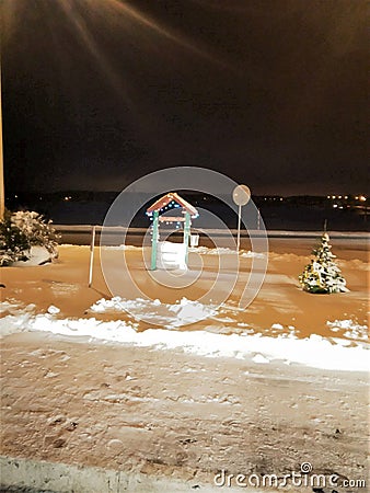 the decorative well is decorated with a color garland, sparks with a row the winter road, a small fir-tree in snow, Stock Photo