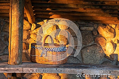 Decorative wicker basket on a wooden table against a stone wall background Stock Photo