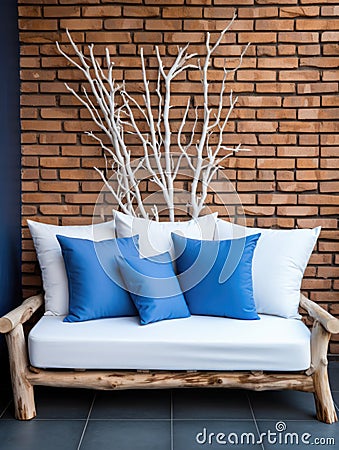 Decorative wooden branches and wood cut composition. White sofa with blue cushions near brick wall. Unique interior design Stock Photo