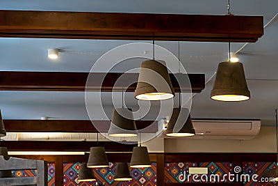 A decorative wooden lampshade with an energy-saving diode lamp is hanging from the ceiling. Unusual designer chandeliers made of Stock Photo