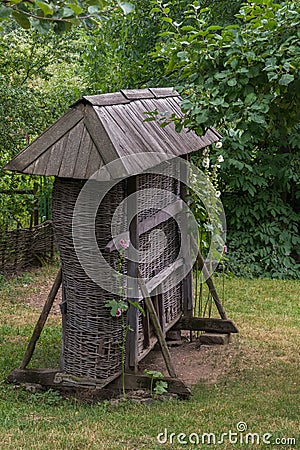 Decorative wooden well with a roof and curling flowers on the sides Stock Photo