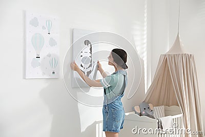 Decorator hanging picture on wall. Children`s room interior design Stock Photo