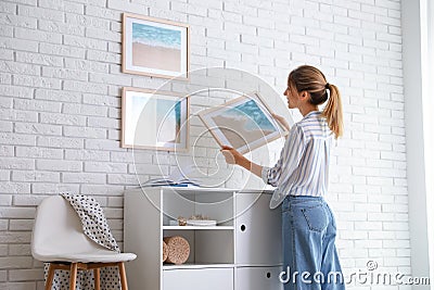Decorator hanging picture on white brick wall in room Stock Photo