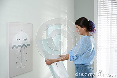 Decorator hanging picture on white wall. Children`s room interior design Stock Photo