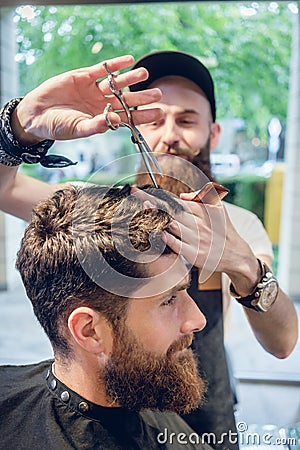 Dedicated hairstylist using scissors and comb while giving a coo Stock Photo