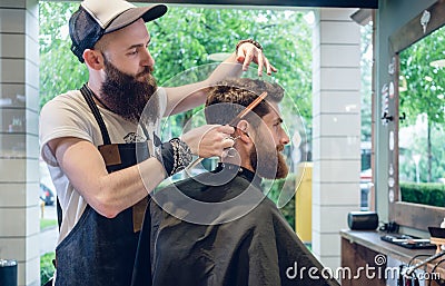 Dedicated hairstylist using scissors and comb while giving a cool haircut Stock Photo