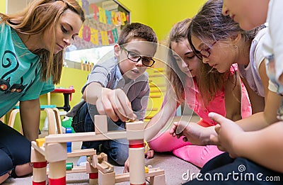 Dedicated kindergarten teacher helping children with the construction of a train Stock Photo