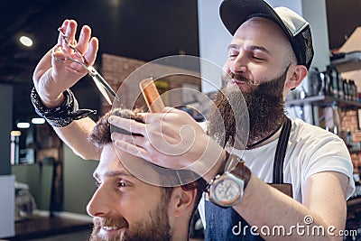 Dedicated hairstylist using scissors and comb while giving a cool haircut Stock Photo