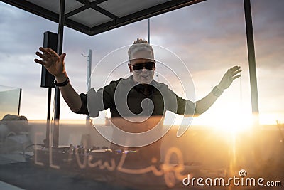 Deejay mixing outdoor with back sun light - Portrait of disc jockey playing disco or deep music for people on beach party at Stock Photo