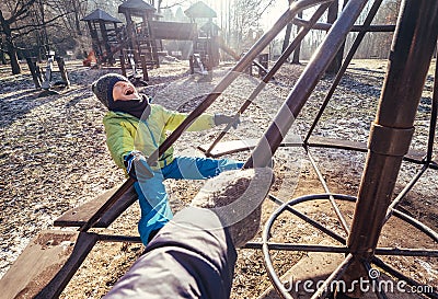 Deep autumn on child playground. Boy turns on the carousel Stock Photo