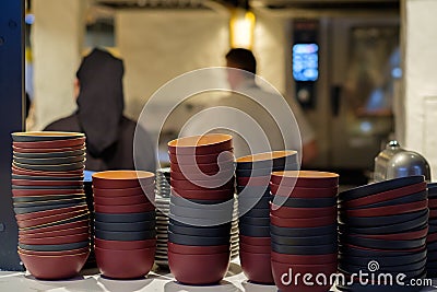 Deep dishes stacked in piles on a kitchen counter in a fast food restaurant. Cooks on a blurred background Stock Photo
