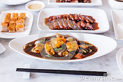 Deep fried snapper fillets stir fried with black pepper, onion, bell pepper, carrot and XO sauce with BBQ Pork and Crispy Pork. Stock Photo