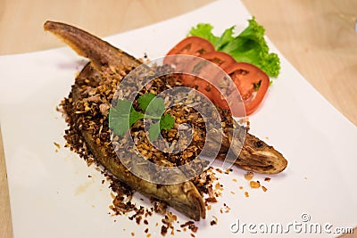 Deep Fried Whisker Sheatfish with Fried Garlic and Sliced Tomato Stock Photo