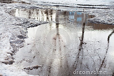 Deep puddle with lumps snow melts on the road in the city Stock Photo