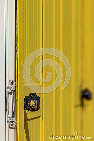 Deep yellow painted beach huts, on sunny but moody day. Blue sky, white clouds, seaside holiday architecture. Stock Photo
