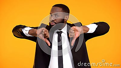 Deeply dissatisfied black man showing double thumbs-down, poor quality service Stock Photo