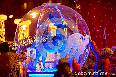A deer standing in a large glass ball. People stand nearby and touch the outside. New year holiday Editorial Stock Photo