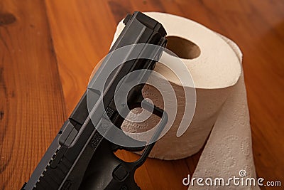 Close up of a pistol laying against toilet paper Stock Photo