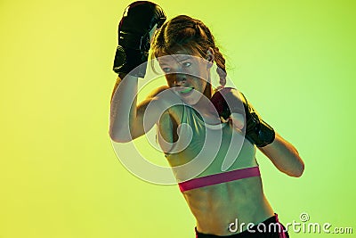 Dynamic portrait of athletic girl, MMA fighter training isolated on gradient yellow-green background in neon. Concept of Stock Photo