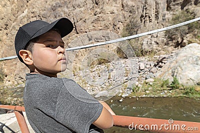 Defiant kid with cup looking at the camera with river and mountains Stock Photo