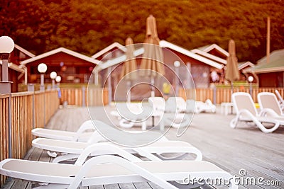 Defocus Autumn landscape recreation deck chairs pool umbrella wooden house fence. Stock Photo