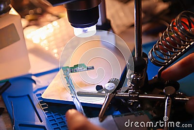 Defocus closeup microscope. Work with a soldering iron. Microelectronics device. Close-up hands of a service worker Stock Photo