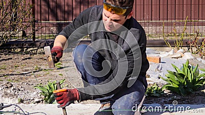 Defocus young construction worker with wrinkled forehead in yellow glasses removing irregularities on floor screed with Stock Photo