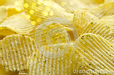 Defocused background with delicious corrugated potato chips with herbs. Selective focus Stock Photo