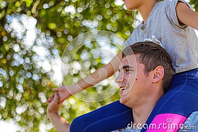 Defocused brother riding sister on back. Portrait of happy girl on man shoulders, piggyback. Girl fly. Family playing Stock Photo