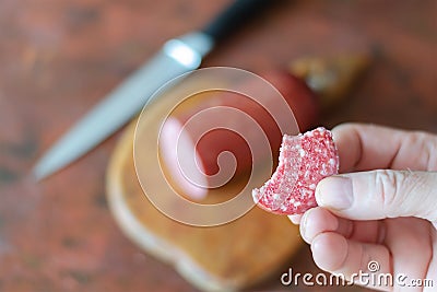 A defocused shot of a hand holding a piece of salami over the ki Stock Photo