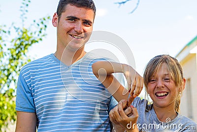 Defocused smiling preteen caucasian girl playing with finger young caucasian man. Summer outdoor blue sky and green tree Stock Photo