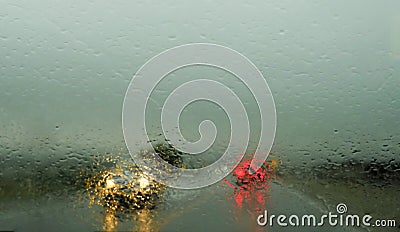 Defocussed traffic viewed through a car windscreen covered in rain,. Focus on raindrops. This is in the fall Stock Photo