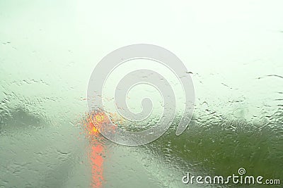 Defocussed traffic viewed through a car windscreen covered in rain,. Focus on raindrops This is in the fall Stock Photo