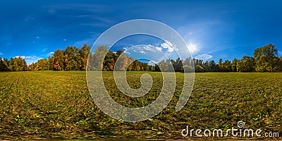 360 by 180 degree spherical panorama of sunny autumnal mowed meadow and yellow forest on its edges with blue sky and Stock Photo