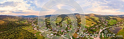 180 degrees panoramic landscape of countryside, aerial drone view of urban village Pidbuzh in Carpathians, Ukraine. Sunset time, Stock Photo