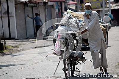 An old man pulls his rickshaw wearing face mask. Editorial Stock Photo