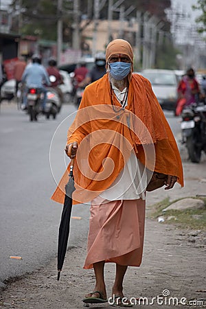 A Sadhu wearing mask going on the road. Editorial Stock Photo