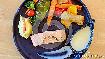 Delectable fried salmon steak with roasted potatoes and grilled vegetables Stock Photo