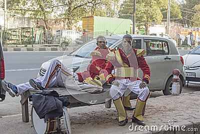 Indian street performers musicians with drums in red dress uniform are resting on the bench Editorial Stock Photo