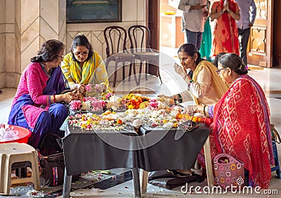 Hindu women weaving flower garlands at ISKCON Delhi Hindu temple Editorial Stock Photo